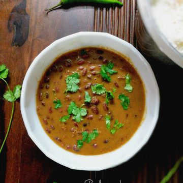 a pot of brown rajma curry in a white bowl on a brown background