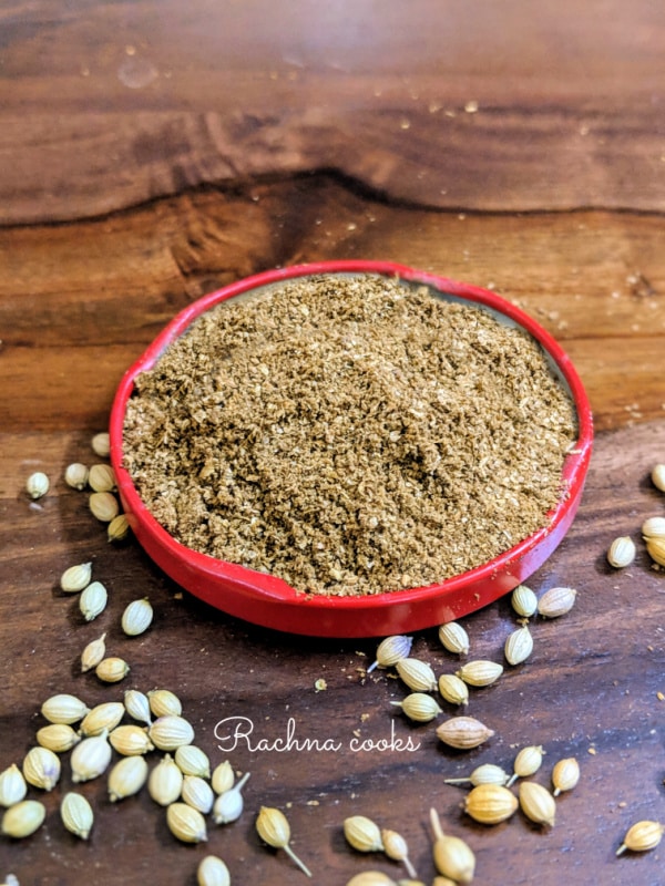 Ground coriander in a red tinged shallow dish with few scattered coriander seeds