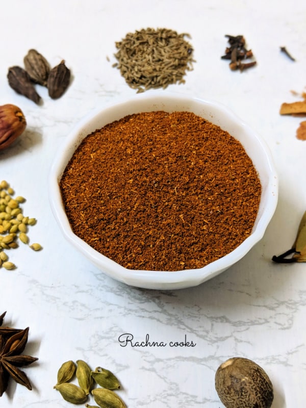 garam masala powder in a bowl surrounded by whole spices.