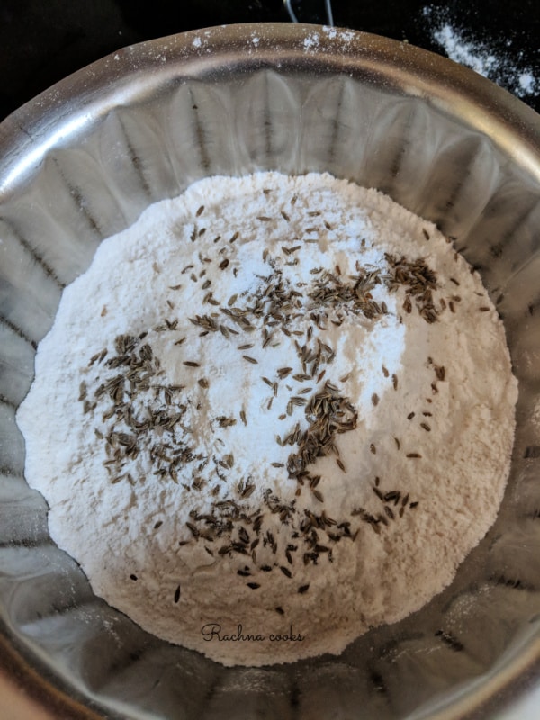 semolina, rice flour and maida with cumin seeds in a shallow bowl.