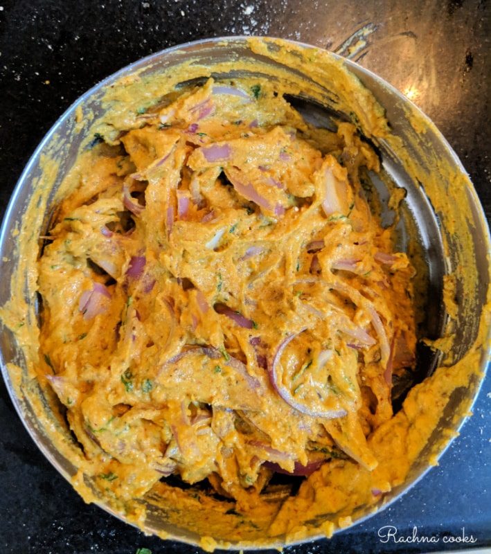 Thick batter for onion pakoda in a shallow pan.