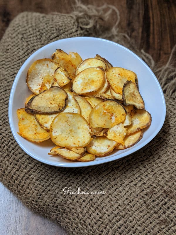 Top shot of cassava chips in a white bowl on a brown background.