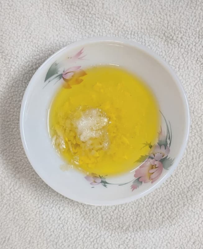 garlic with olive oil, vinegar, salt and sugar in a white bowl