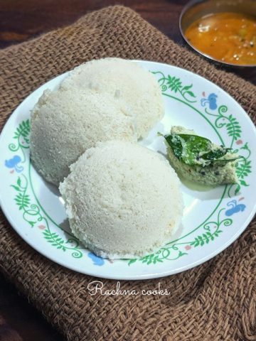 3 idlis served on a white plate with coconut chutney.