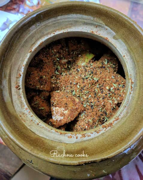 Raw mango pieces coated with spice mix in a ceramic pot.
