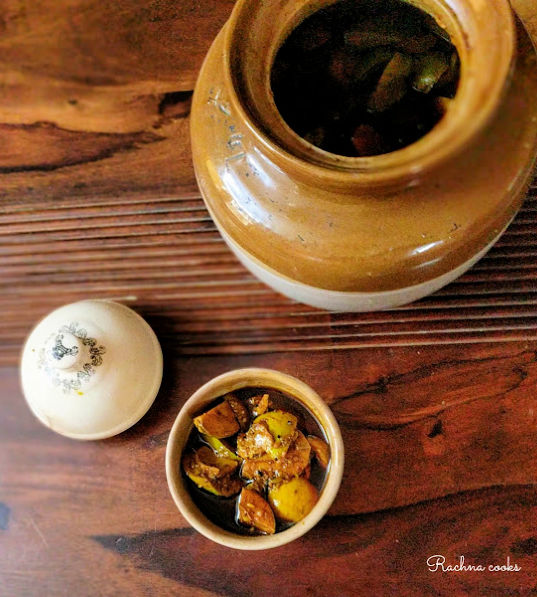 North Indian aam ka achaar in a ceramic pot with a larger pot visible in the background.