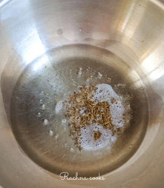 Oil with cumin seeds in a pan.