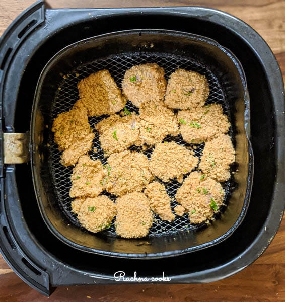 Air fryer basket showing breaded chicken nuggets arranged in one layer.