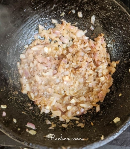 A cast iron wok showing sauteed onion and ginger garlic