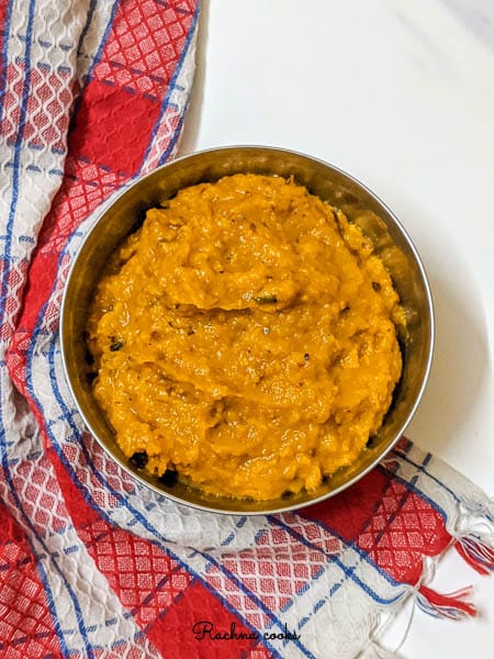 Orange pumpkin puree in a bowl with a red and white napkin in background.