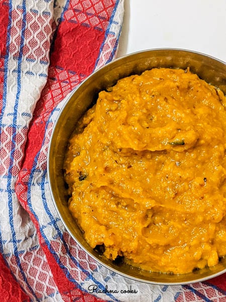 Thick orange pumpkin puree in a bowl with a checked red and white napkin in background