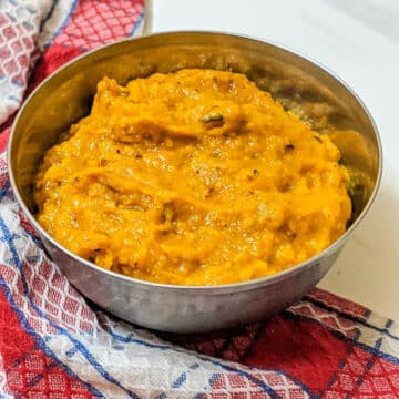 Thick orange pumpkin puree in a bowl with a checked red and white napkin in background