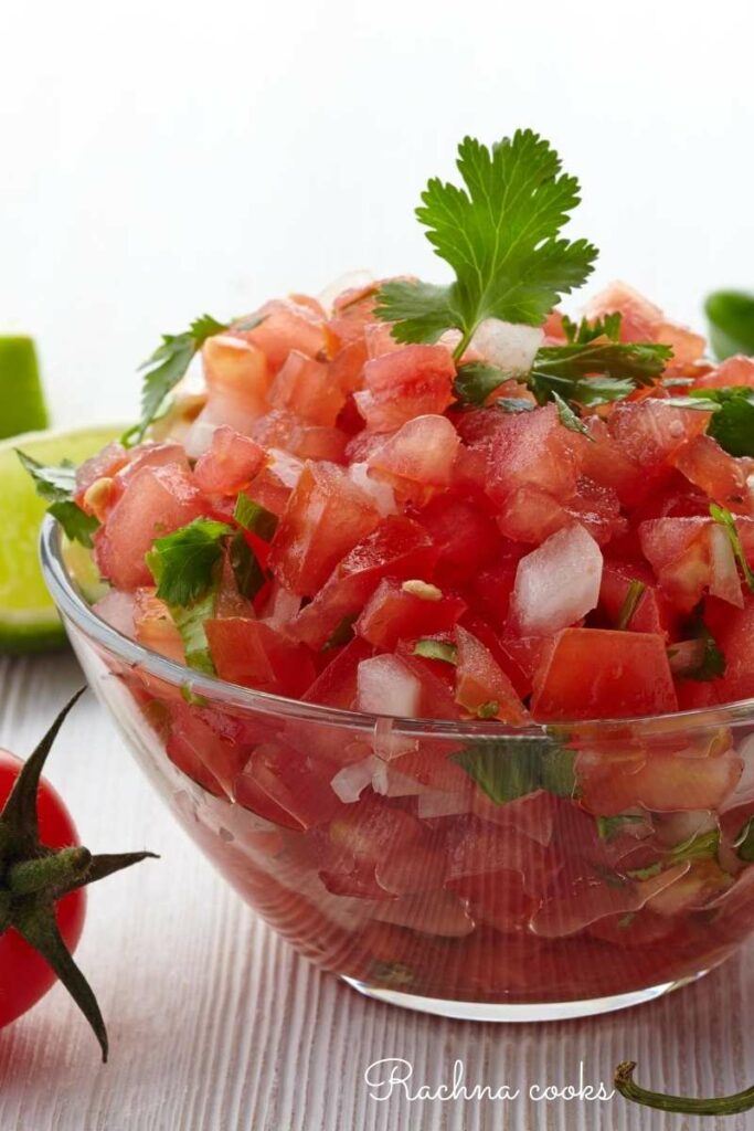 Vibrant red tomato salsa with onion and cilantro bits in a transparent bowl.