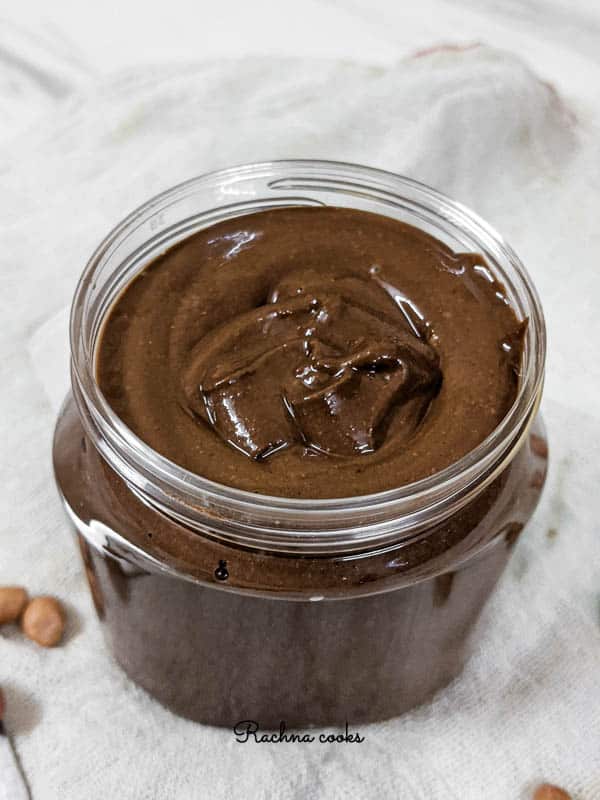 a jar of brown shiny chocolate peanut butter on a white background