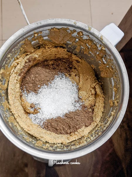 Cocoa powder and sugar added to blended peanuts in a blender.