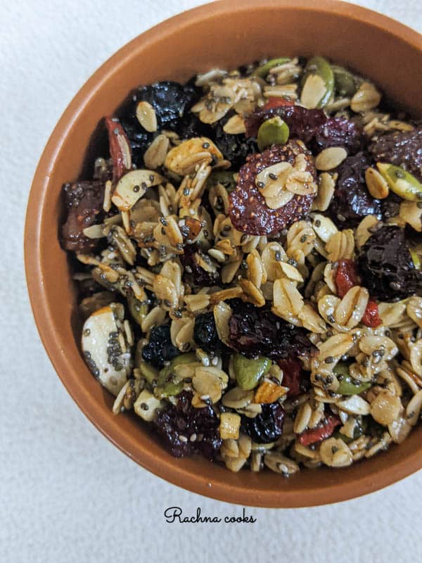 Close up of tasty granola with berries and oats in a brown round bowl on a white background