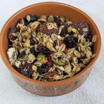 tasty granola with berries and oats in a brown round bowl on a white background