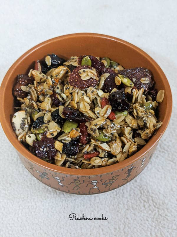 tasty granola with berries and oats in a brown round bowl on a white background