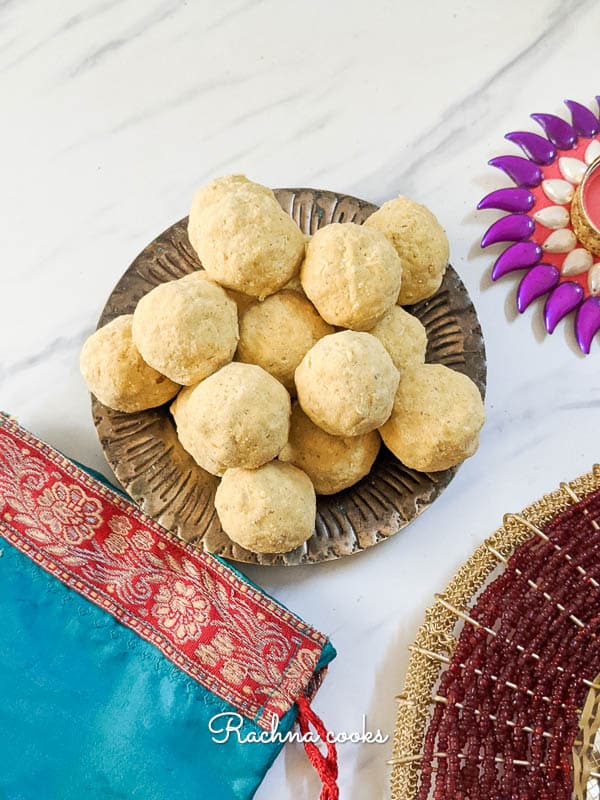 beautiful besan ladoos on a brass plate with an ethnic background.