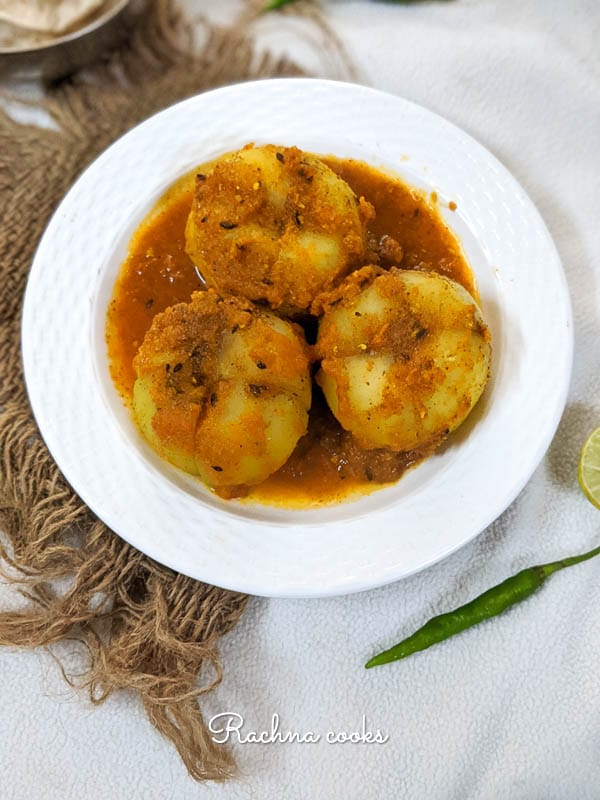 Bharwa tinda or stuffed apple gourd in a curry on a white plate.