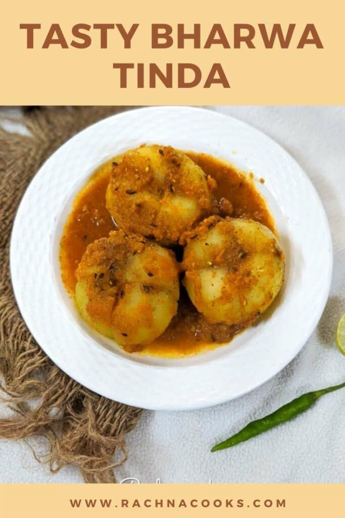 Bharwa tinda or stuffed apple gourd in a curry on a white plate.