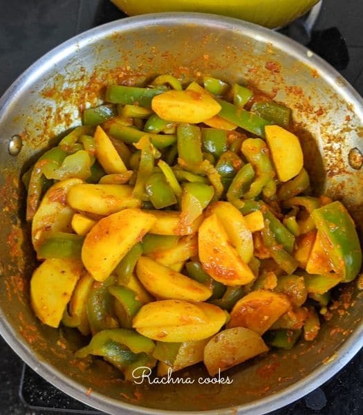 Aloo capsicum mixed together in a wok.