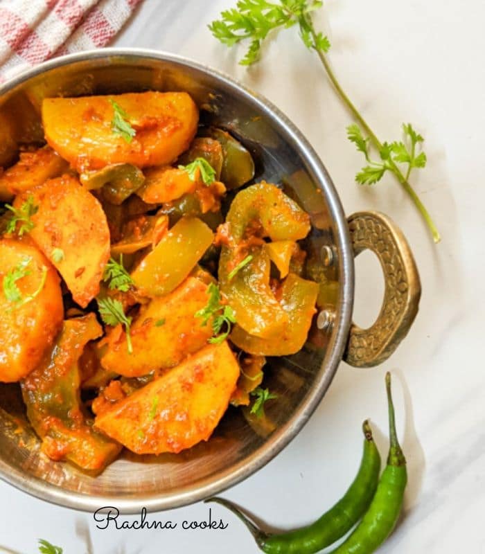 aloo capsicum sabzi in a kadhai with a checked red napkin in the background