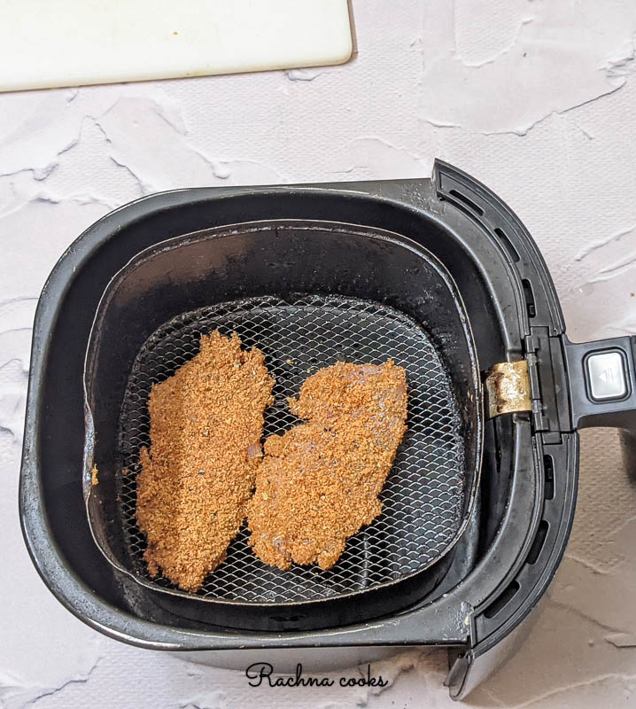 Breaded tilapia fillets in an air fryer basket ready for air frying