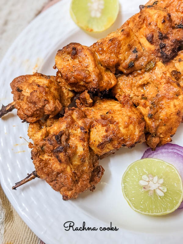 Air fryer chicken tikka cubes with lemon wedges and onion rings.