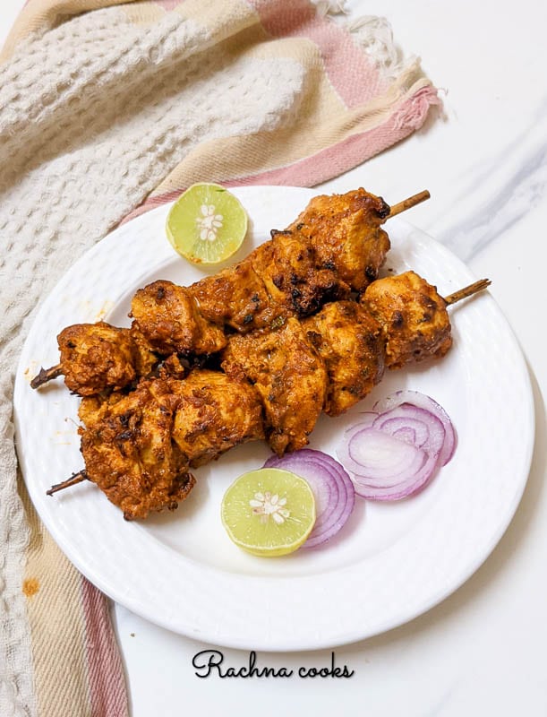 Air fryer chicken tikka cubes with lemon wedges and onion rings.