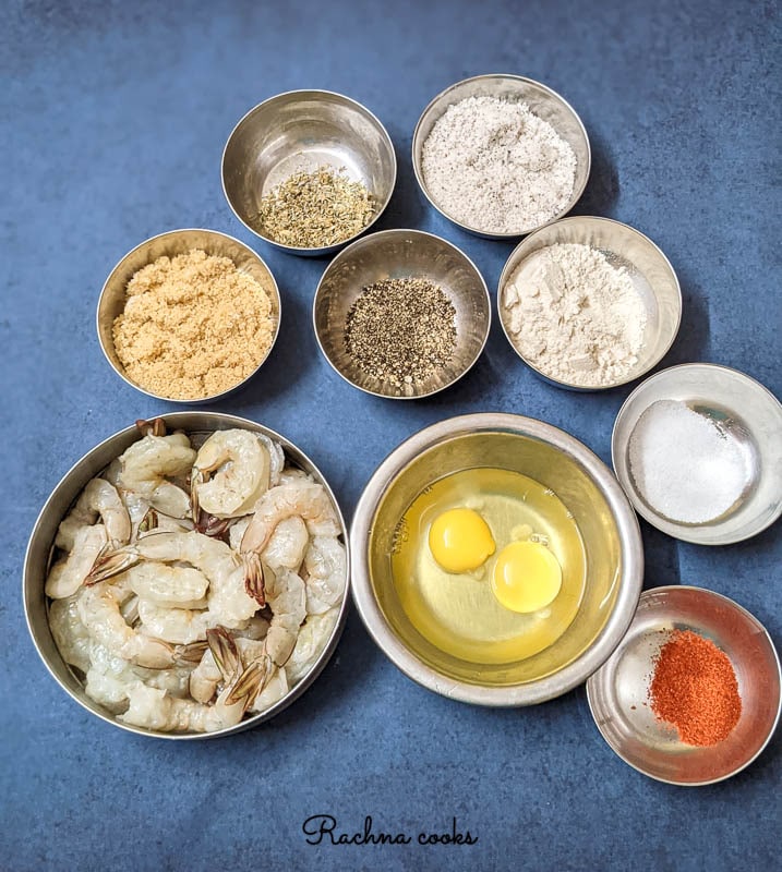 Ingredients to make coconut shrimp -- peeled shrimp, eggs, herbs, breadcrumbs, coconut flakes, flour.