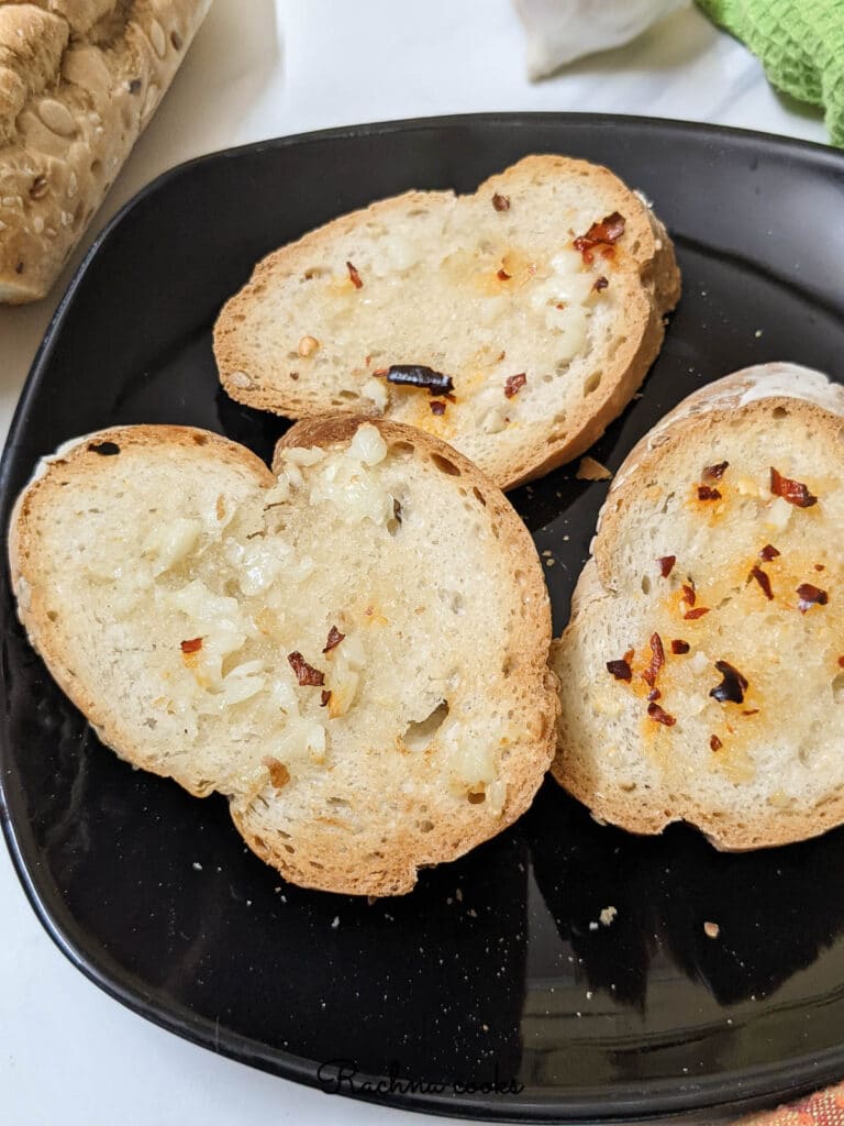 Garlic bread slices toasted in air fryer on a black plate.
