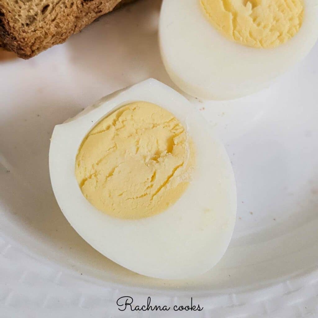 air fryer hard boiled egg cut into two after peeling on a white plate.
