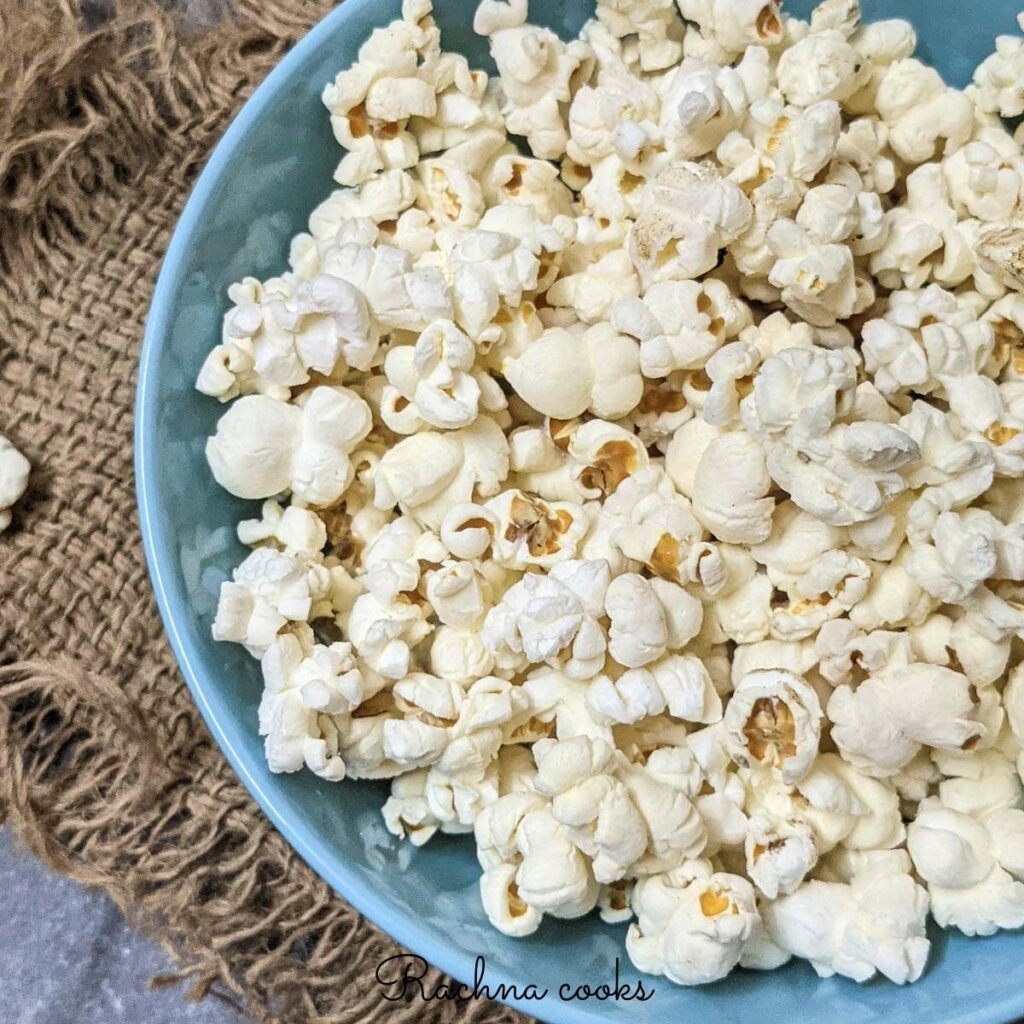 Close up of popcorn in a blue bowl with a brown mat in the background.