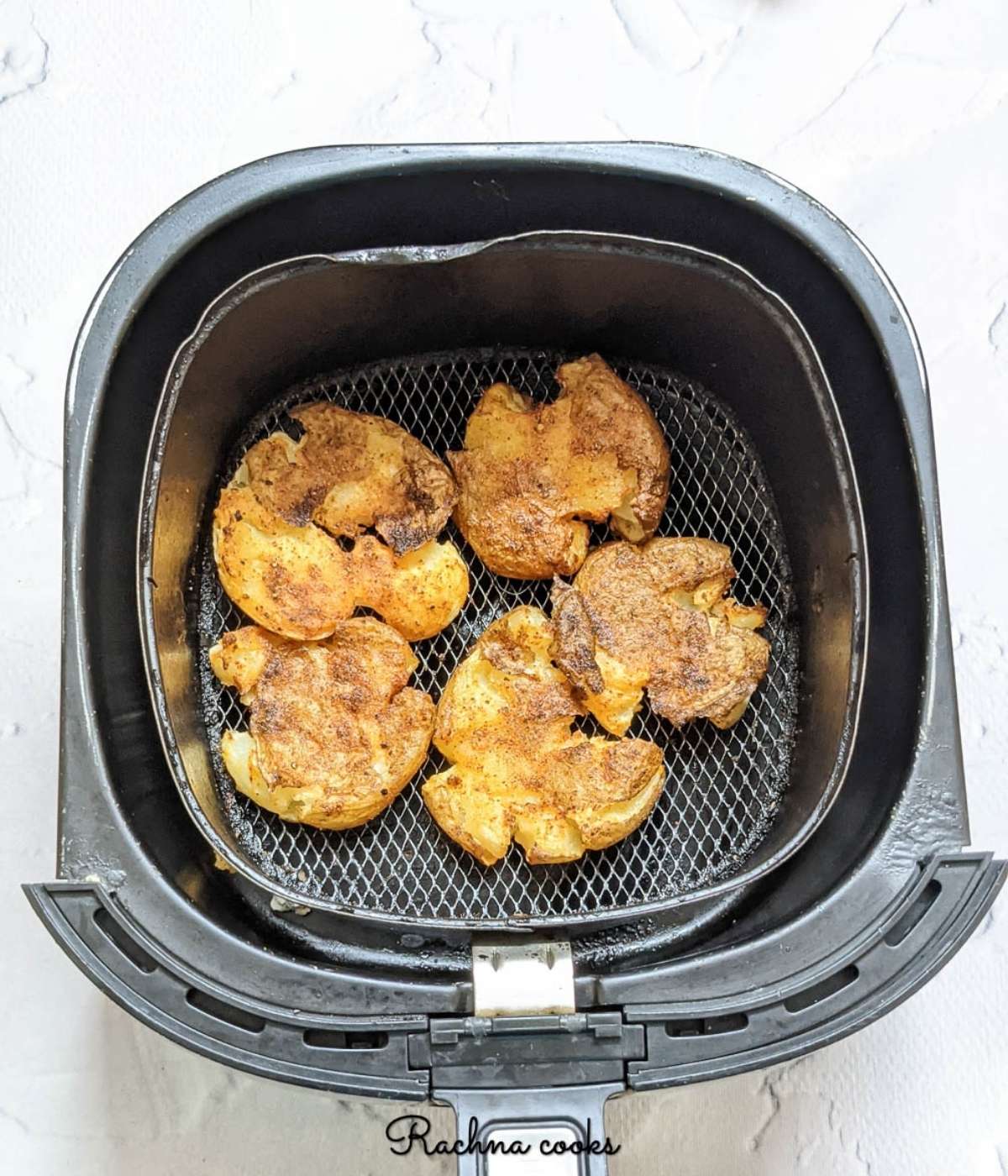 air fried smashed potatoes golden and crispy in air fryer basket.