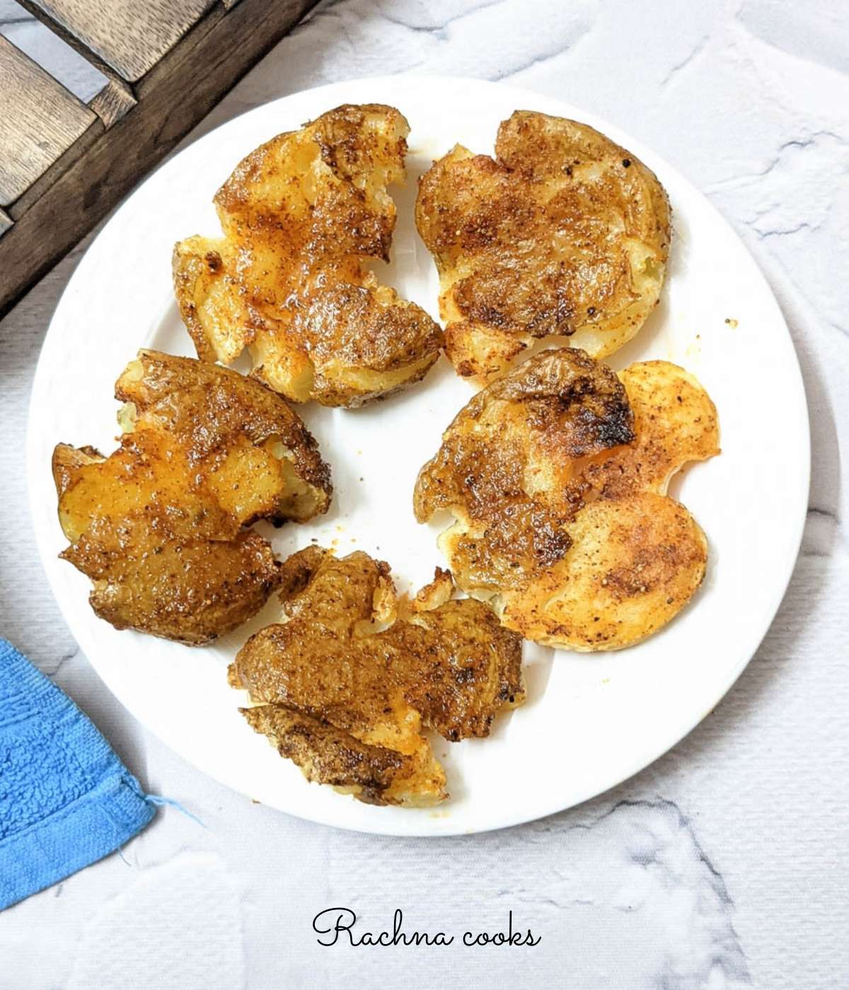
golden brown air fryer smashed potatoes on a white plate. 