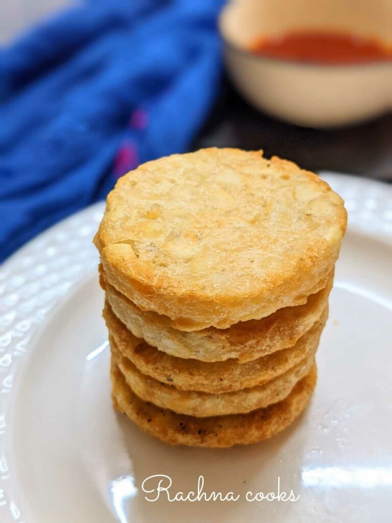 5 stacked air fried hash brown patties on a white plate.