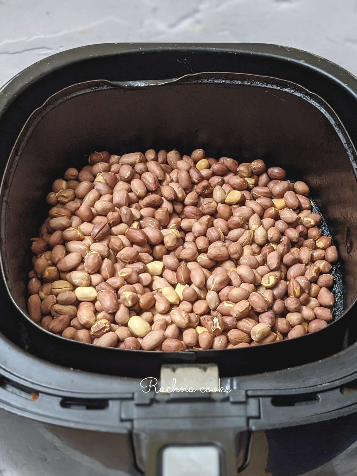 Peanuts in air fryer baskets for air frying.