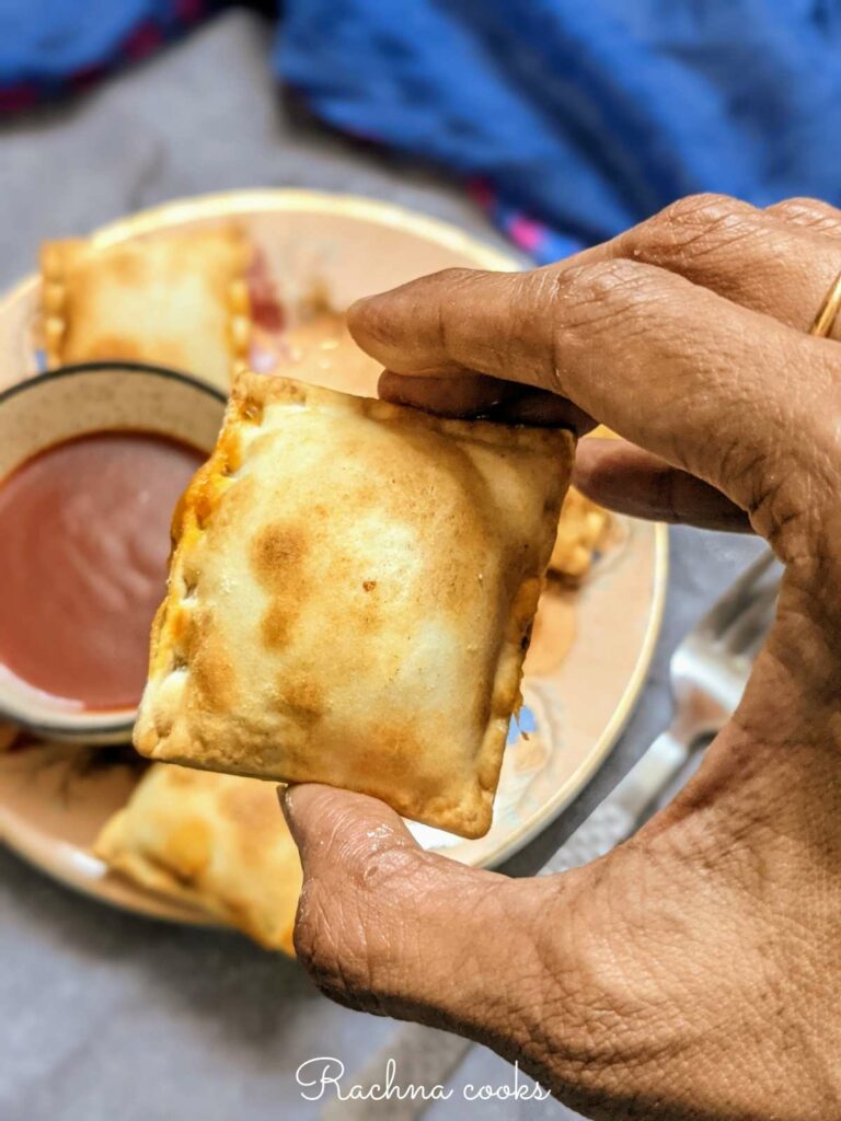 Close up of air fried frozen pizza roll on a plate with a bowl of ketchup.