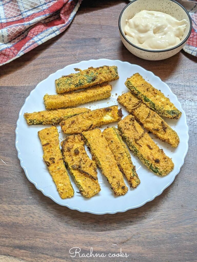 air fried zucchini fries in a white plate with mayo sauce.