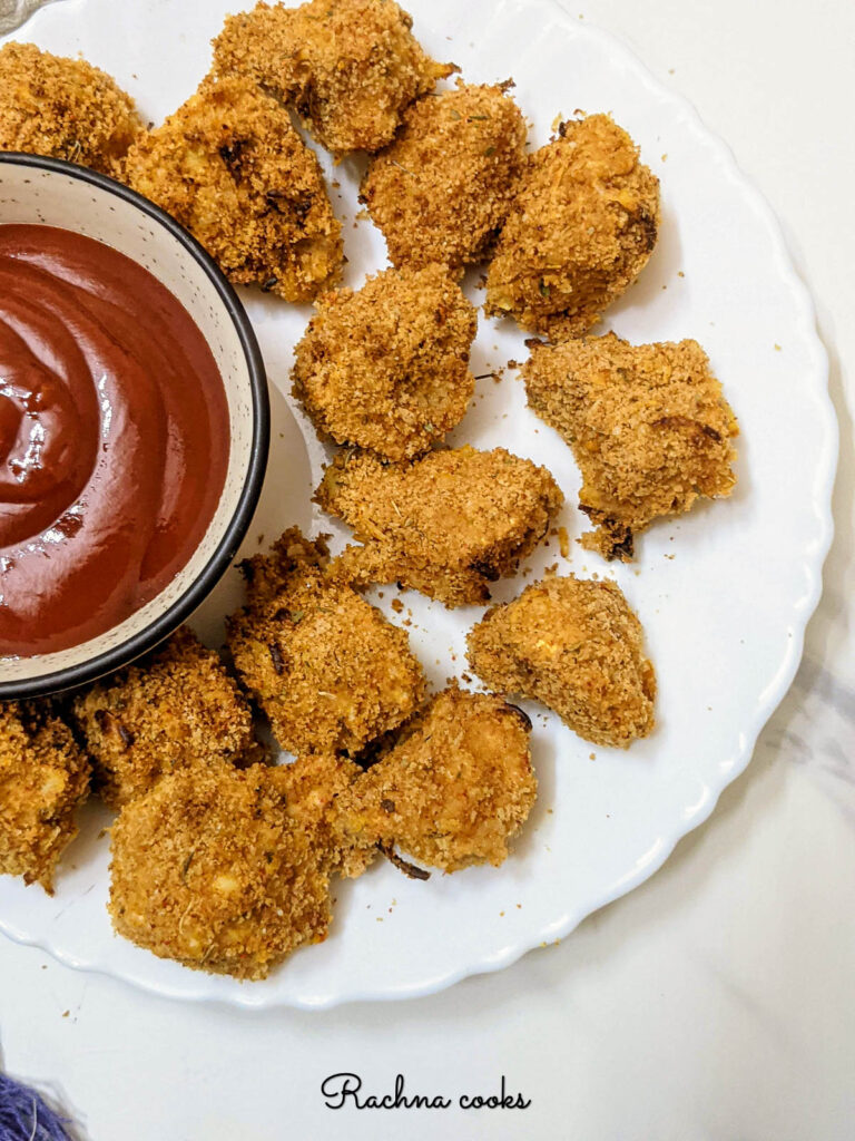Air fried breaded mushrooms on a white plate with a bowl of ketchup.