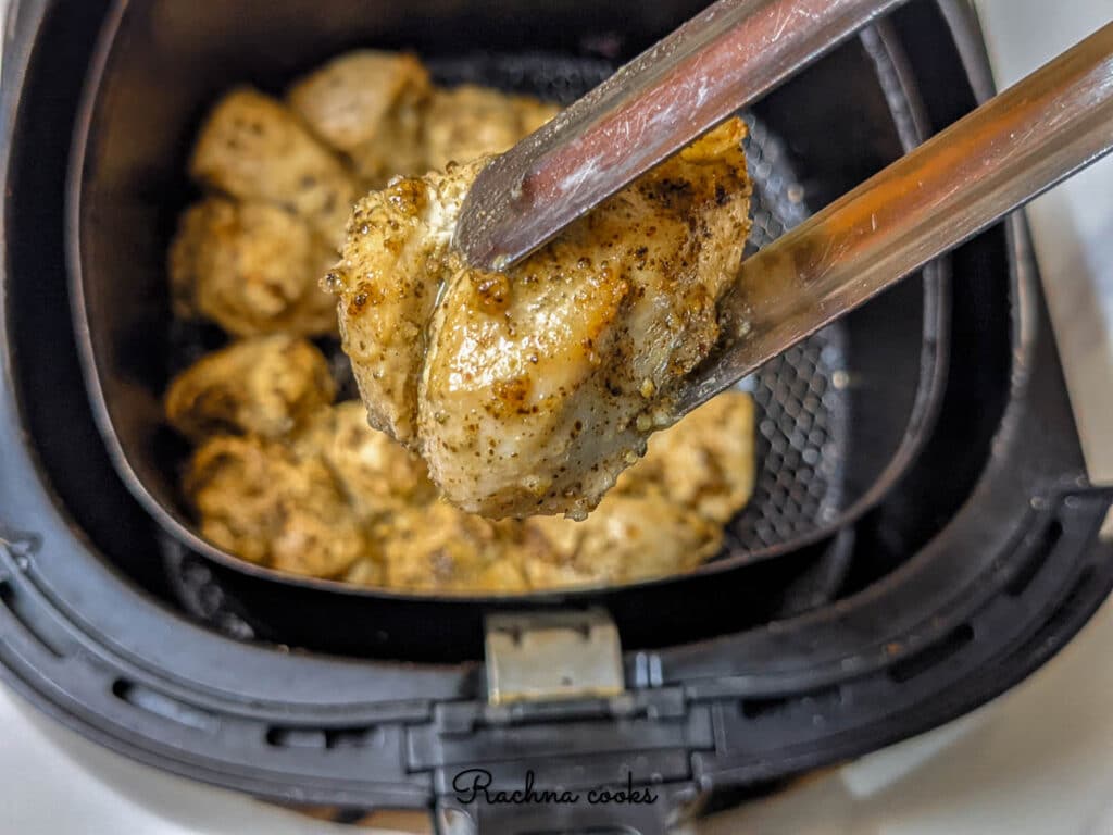 Delicious air fried lemon pepper chicken after air frying in air fryer basket.