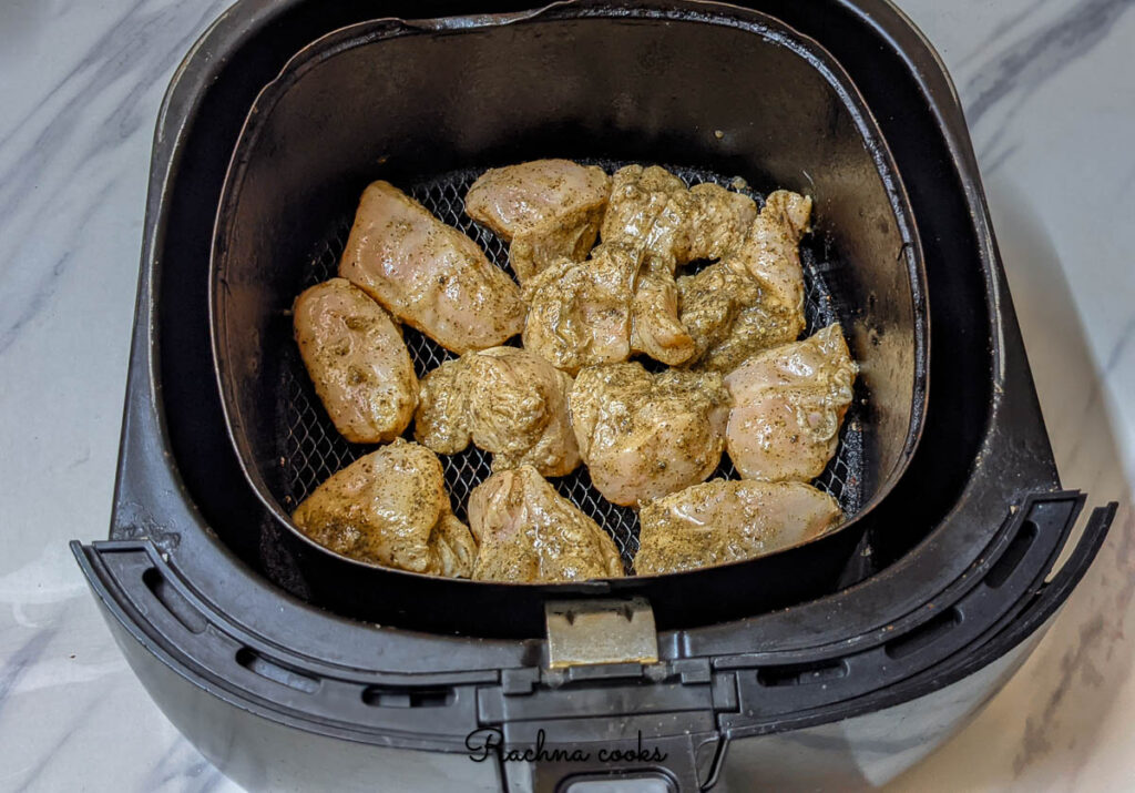 Marinated lemon pepper chicken cubes ready for air frying in air fryer basket.