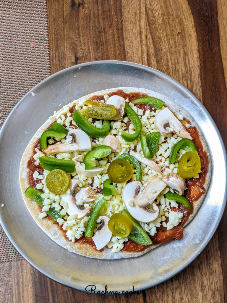 Assembled pizza with pizza crust, cheese, tomato sauce and toppings ready to air fry.