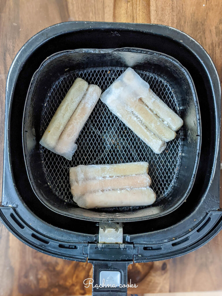 Frozen sausages in air fryer basket ready for air frying.