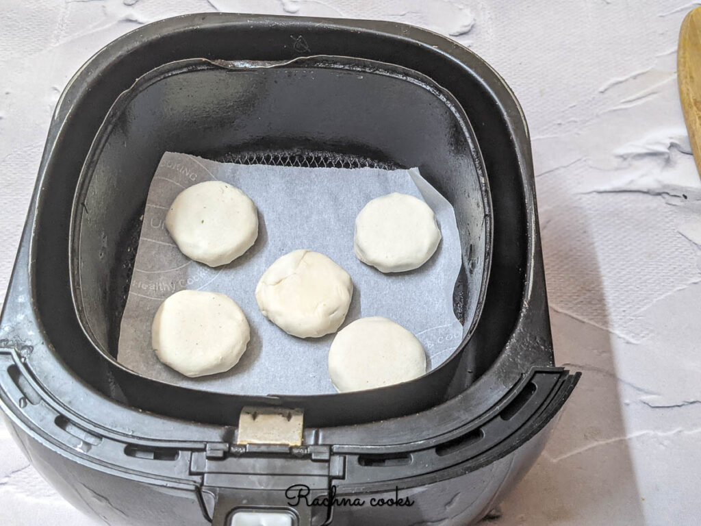 Air fryer basket with parchment paper and prepared Oreos placed on them.