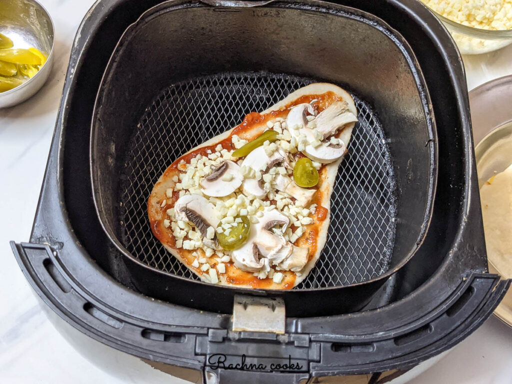 naan pizza in air fryer basket ready to air fry