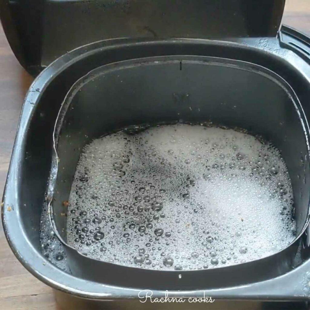 air fryer basket soaked in soapy water for cleaning.
