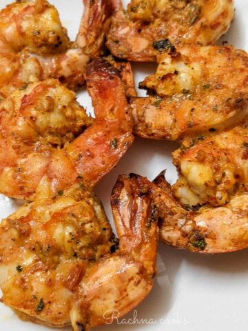 tandoori shrimp skewers on a white plate.
