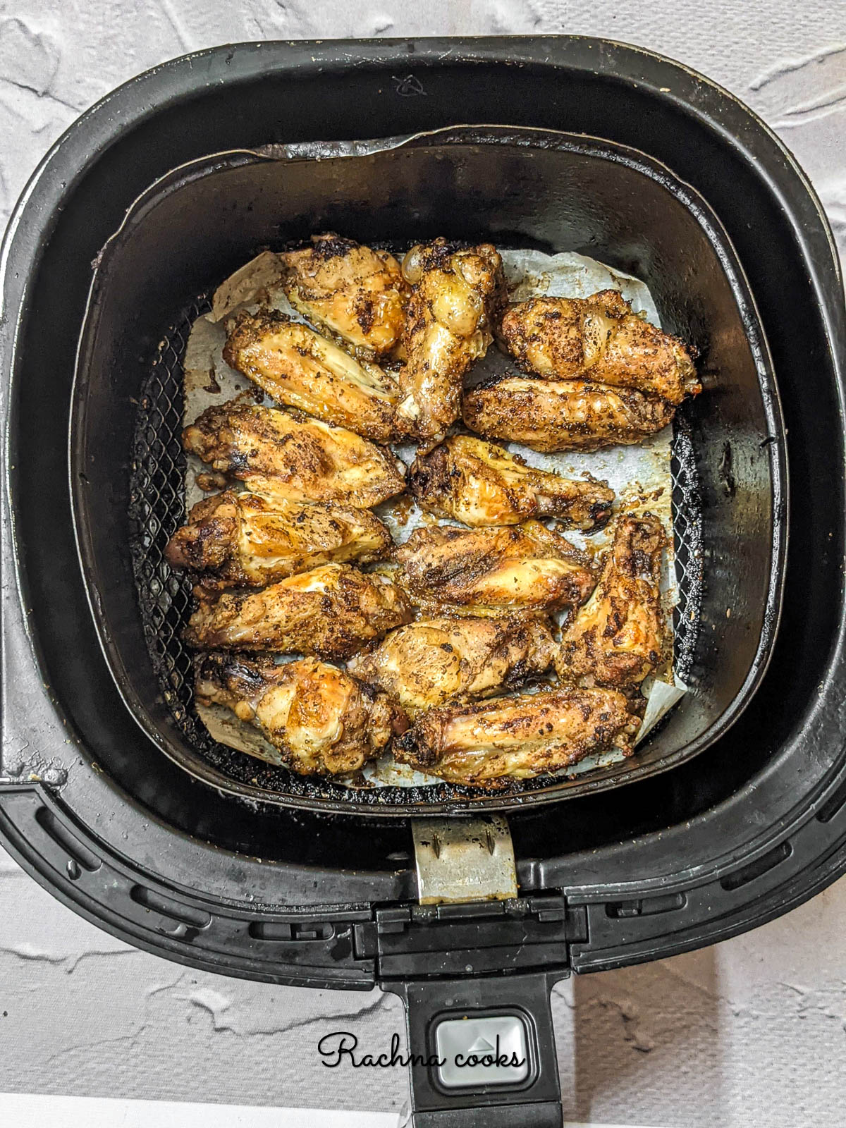 wings after air frying in air fryer basket lined with parchment paper